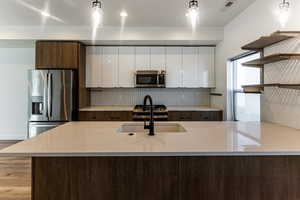 Kitchen with white cabinetry, hanging light fixtures, and appliances with stainless steel finishes