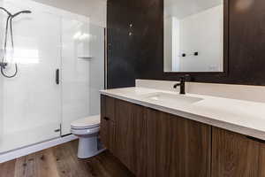 Bathroom with toilet, vanity, a shower with door, and hardwood / wood-style floors