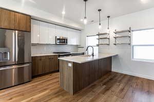 Kitchen with hardwood / wood-style floors, pendant lighting, sink, white cabinetry, and stainless steel appliances