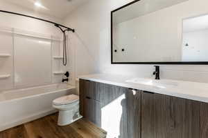 Full bathroom featuring toilet, shower / bathtub combination, hardwood / wood-style floors, and vanity