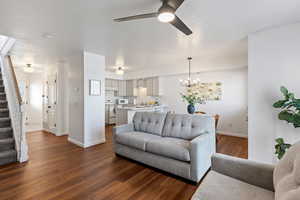 Living room with dark hardwood / wood-style floors, sink, and ceiling fan with notable chandelier