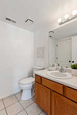 Bathroom with toilet, a textured ceiling, tile patterned floors, and vanity