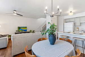 Dining area featuring ceiling fan with notable chandelier and dark wood-type flooring