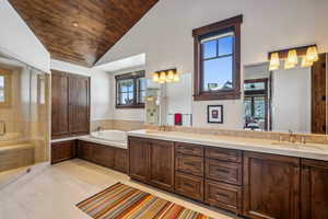 Bathroom featuring a wealth of natural light, tile patterned floors, vanity, and vaulted ceiling