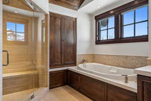 Bathroom with separate shower and tub, vanity, and vaulted ceiling