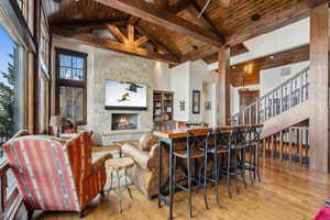 Living room featuring high vaulted ceiling, beam ceiling, a stone fireplace, and wood ceiling