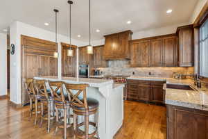 Kitchen featuring appliances with stainless steel finishes, a center island, sink, hanging light fixtures, and custom range hood