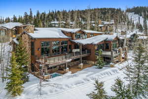 Snow covered back of property with a balcony