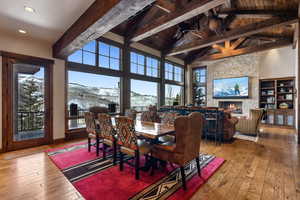 Dining room featuring wood-type flooring, a fireplace, beamed ceiling, and wooden ceiling