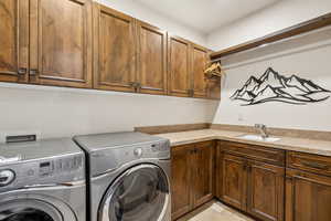 Clothes washing area with sink, separate washer and dryer, and cabinets