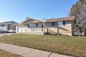 View of front of property with covered porch and a front yard