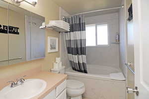 Full bathroom with toilet, vanity, and shower / bath combo