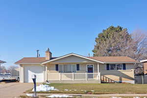 Single story home featuring a front lawn, covered porch, and a garage