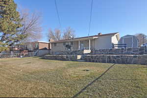 Back of house with a yard and a storage shed