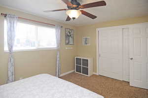 Bedroom with ceiling fan, a closet, and carpet flooring