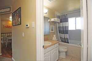 Full bathroom with tile patterned flooring, toilet, vanity, and shower / tub combo with curtain