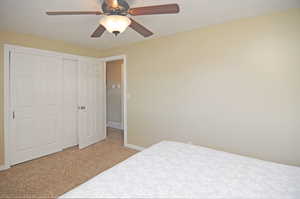 Bedroom featuring ceiling fan, a closet, and light colored carpet