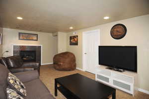 Living room with carpet floors, a tiled fireplace, and a textured ceiling