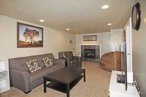 Living room featuring light carpet, a tiled fireplace, and a textured ceiling