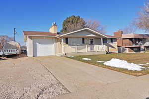 Ranch-style house with covered porch, a front lawn, and a garage