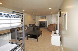 Living room with light colored carpet, a textured ceiling, and a fireplace