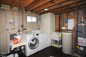 Clothes washing area featuring water heater, dark wood-type flooring, independent washer and dryer, and sink