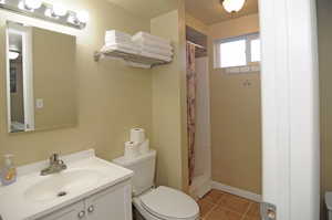 Bathroom featuring walk in shower, vanity, tile patterned flooring, and toilet