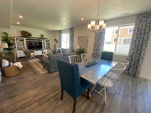 Dining area with dark hardwood / wood-style floors and a notable chandelier