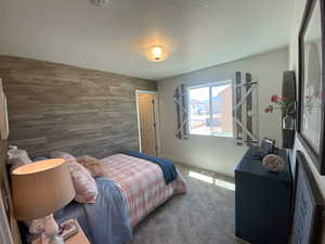 Bedroom featuring a textured ceiling, wooden walls, and dark colored carpet