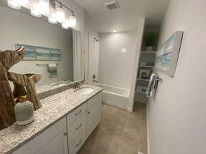 Bathroom featuring tile patterned floors, tiled shower / bath combo, and vanity