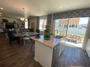 Kitchen featuring white cabinets, sink, hanging light fixtures, a kitchen island with sink, and stainless steel dishwasher