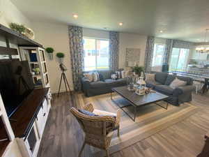 Living room featuring a textured ceiling, dark wood-type flooring, and a chandelier