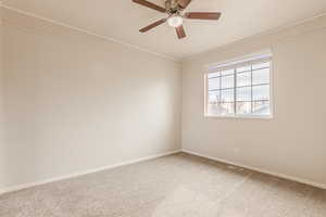 Carpeted empty room with ceiling fan and ornamental molding