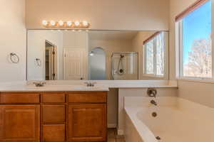 Bathroom featuring ceiling fan, tile patterned flooring, separate shower and tub, and vanity