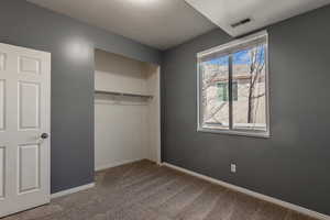 Unfurnished bedroom with a textured ceiling, a closet, and carpet