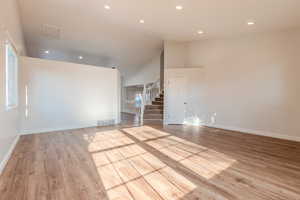 Unfurnished living room with light hardwood / wood-style floors and high vaulted ceiling