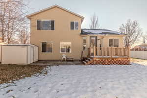 Snow covered house featuring a deck and a shed