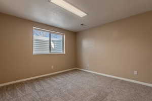 Empty room featuring a textured ceiling and carpet flooring