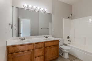 Full bathroom featuring toilet, vanity, tile patterned floors, and shower / tub combination