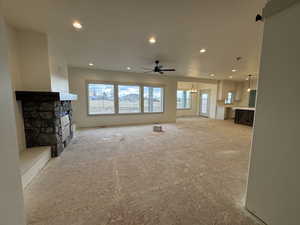 Living room with ceiling fan with notable chandelier, a fireplace, and plenty of natural light