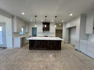 Kitchen featuring light stone counters, a spacious island, and decorative light fixtures