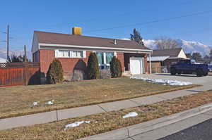 View of front facade featuring a front lawn, a garage, and a mountain view