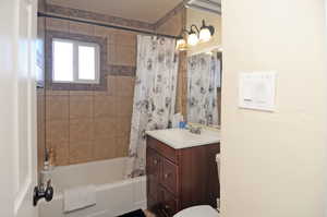 Full bathroom with toilet, shower / bath combination with curtain, and vanity