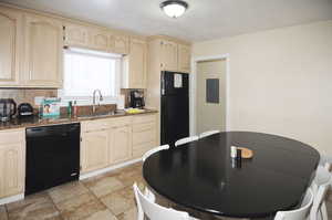 Kitchen featuring black appliances, dark stone countertops, tasteful backsplash, sink, and electric panel