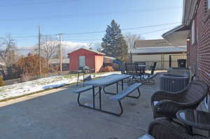 View of patio with a shed and cooling unit