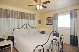 Bedroom featuring ceiling fan and dark colored carpet