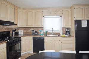 Kitchen with black appliances, light tile patterned floors, decorative backsplash, and sink