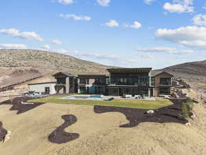 Rear view of house featuring a patio area, a balcony, a mountain view, a jacuzzi, and an outdoor pool