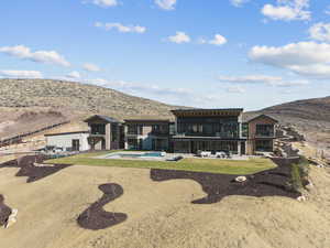 Back of property featuring a patio, a balcony, a mountain view, a hot tub, and an outdoor pool
