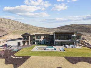 Rear view of property featuring a patio, a balcony, and a lawn
